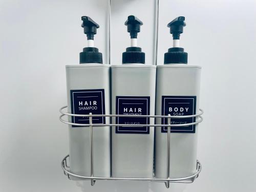 a group of four bottles of hair products in a rack at Hostel SAMURISE 81INN in Fujikawaguchiko