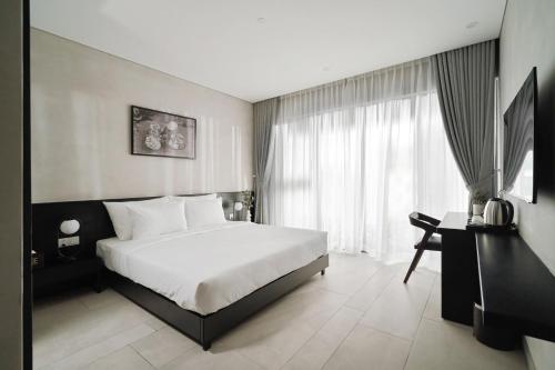 胡志明市的住宿－Triple E Hotel Metro Ben Thanh，卧室配有一张白色大床和一张书桌