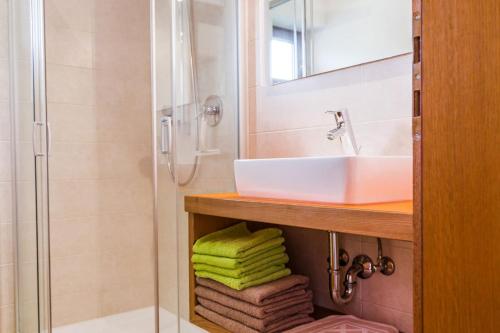 La salle de bains est pourvue d'un lavabo, d'une douche et de serviettes. dans l'établissement Ferienwohnung Lanz 2, à Lana