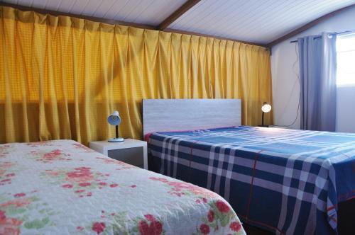 una camera con due letti e tende gialle di Casa Com Quatro Dormitórios Pertinho Do Mar Em Capão Da Canoa a Capão da Canoa