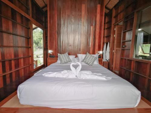 a bedroom with a white bed with a white ribbon on it at Pan's farm แบ่งปันฟาร์ม in Ban San Phaya Loei Luang