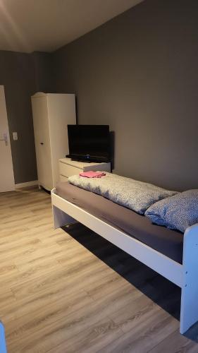 a bedroom with a bed and a dresser with a refrigerator at Flensburg Strandnah in Flensburg