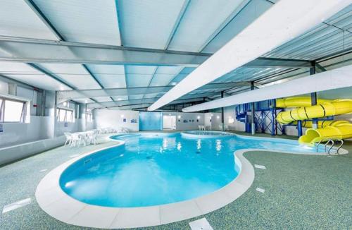 a large swimming pool with yellow slides in a building at Olive-Grove in Kent