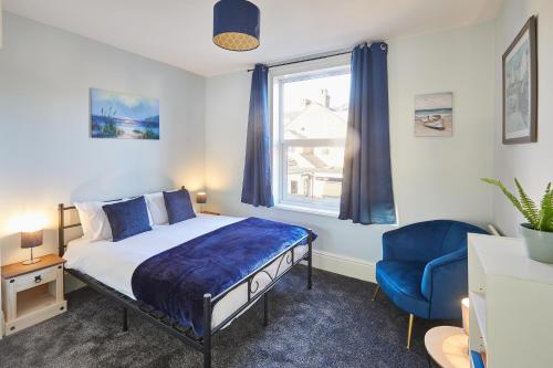 um quarto com uma cama e uma cadeira azul e uma janela em Host & Stay - Holyrood Lodge em Bridlington