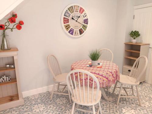a dining room table with chairs and a clock on the wall at Stunning Cottage on the Edge of the Cotswolds in Charfield