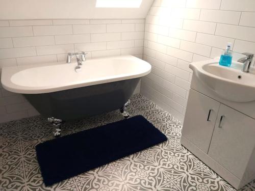 a bathroom with a sink and a bath tub and a sink at Stunning Cottage on the Edge of the Cotswolds in Charfield
