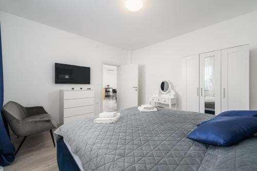 a white bedroom with a bed and a chair at Villa Jolanda in Umag