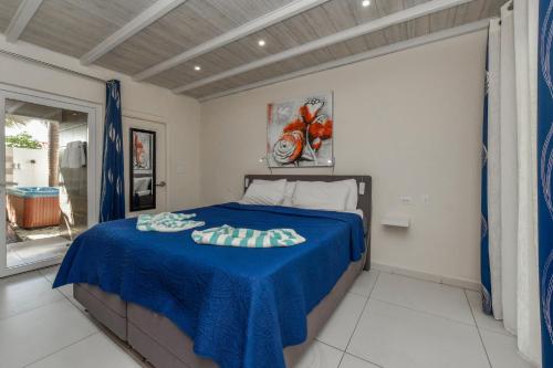 a bedroom with a bed with a blue blanket at Boutique Hotel Swiss Paradise Aruba Villas and Suites in Palm-Eagle Beach