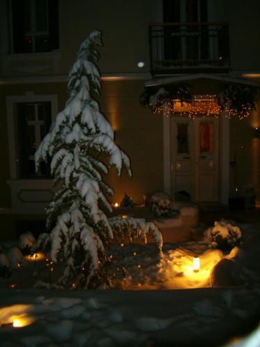 a snow covered christmas tree in a yard with a candle at room "butterfly" in a neoclassical house in Kastoria