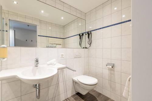 a white bathroom with a sink and a toilet at Hotel Flamatt in Flamatt
