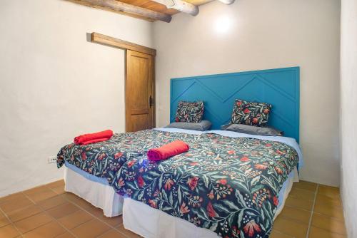 a bedroom with a bed with a blue headboard and red pillows at Casa La Cuadra in Telde