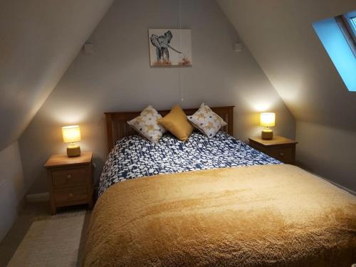 a bedroom with a large bed with two lamps on tables at Relaxing Retreat on the edge of the Cotswolds in Kingswood