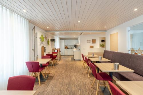 um restaurante com mesas de madeira e cadeiras vermelhas em Hotel Flamatt em Flamatt