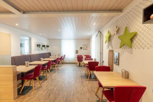 a restaurant with wooden tables and red chairs at Hotel Flamatt in Flamatt