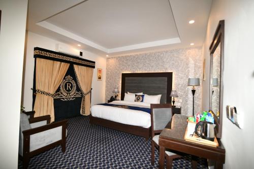 a hotel room with a bed and a desk and a bed and a room at Royal Regency Hotel in Islamabad