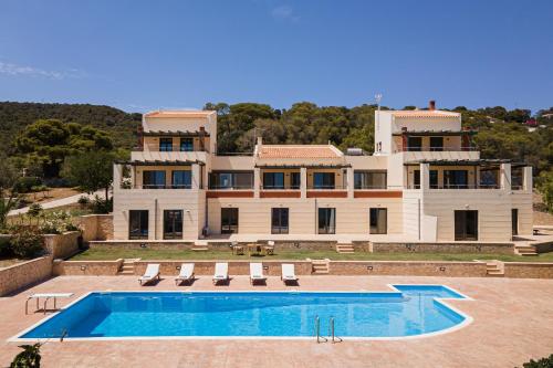 a large house with a swimming pool in front of it at Aphaia Villa & Residences Aegina in Agia Marina Aegina