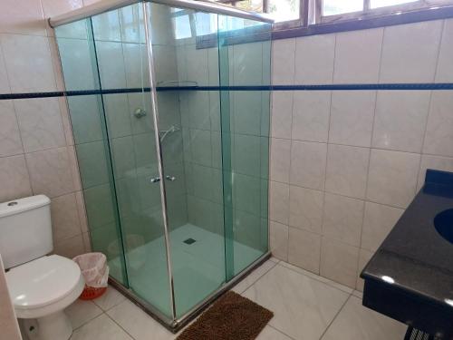 a glass shower in a bathroom with a toilet at Diversão, churrasco e piscina - Praia de Ipitanga in Salvador