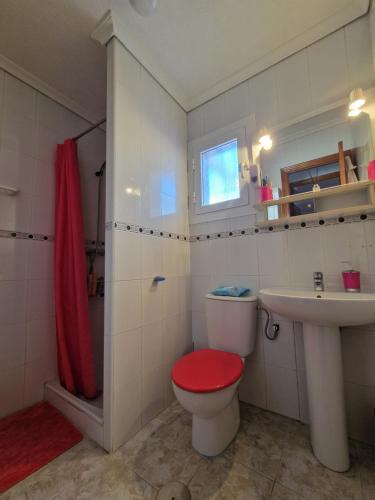 a bathroom with a red toilet and a sink at Villa pink Ambience in Mazarrón