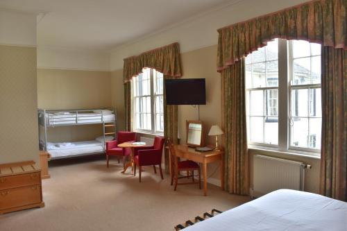 a bedroom with a bed and a desk and a bed and window at Green Hotel in Kinross