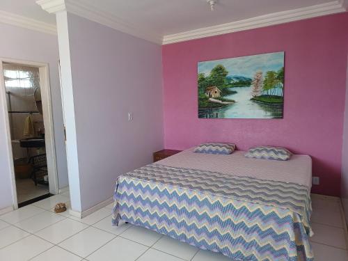 a bedroom with a bed and a painting on the wall at Diversão, churrasco e piscina - Praia de Ipitanga in Salvador