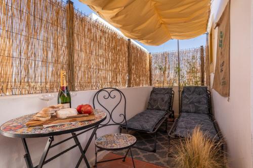 uma pequena varanda com uma mesa e cadeiras e uma garrafa de vinho em Arty Vintage Townhouse with Rooftop Shower & Sun Loungers em Olhão