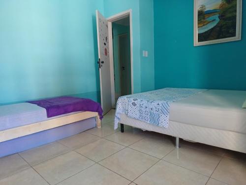 Duas camas num quarto com paredes azuis em Diversão, churrasco e piscina - Praia de Ipitanga em Salvador