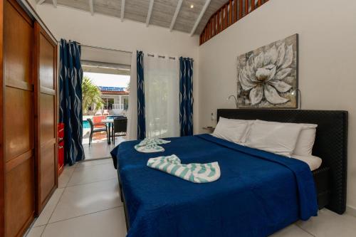 a bedroom with a bed with a blue blanket at Boutique Hotel Swiss Paradise Aruba Villas and Suites in Palm-Eagle Beach