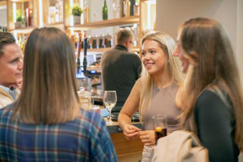 a group of people standing around a bar at The Woodside in Doune