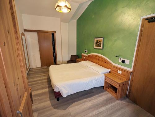 a bedroom with a bed and a green wall at Hotel Cova in Pellizzano