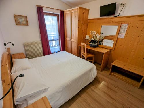 a bedroom with a bed and a table and a desk at Hotel Cova in Pellizzano