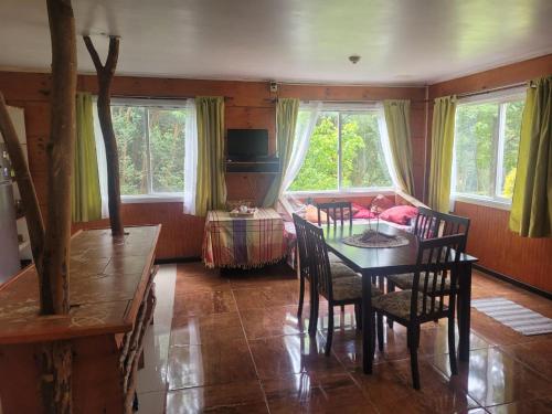 a dining room with a table and chairs and windows at Cabañas Tepual in Puerto Montt