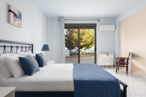 a bedroom with a large bed and a sliding glass door at Aphaia Villa & Residences Aegina in Agia Marina Aegina