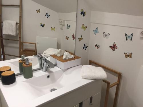 La salle de bains est pourvue d'un lavabo aux papillons sur le mur. dans l'établissement Maison H 3 personnes Honfleur, à Honfleur