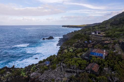 an aerial view of the ocean and a house on a cliff at Casa do Caramba - The Dream House in São Roque do Pico