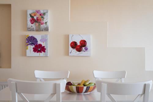 a dining room with three chairs and a bowl of fruit at Aphaia Villa & Residences Aegina in Agia Marina Aegina