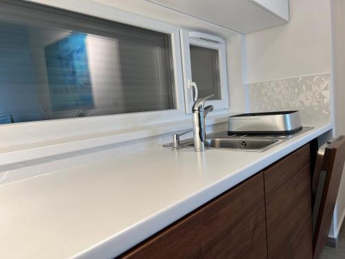a kitchen counter with a sink and a window at Lela lakeside apartman a vizek szerelmeseinek in Balatonlelle