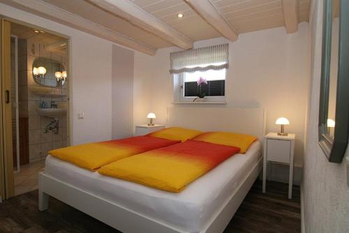 a bedroom with a large bed with two yellow and red blankets at Appartement Rehder in Hörnum