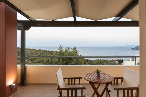 a balcony with a table and chairs and a view of the ocean at Aphaia Villa & Residences Aegina in Agia Marina Aegina