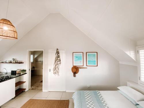 una camera da letto bianca mansardata con letto e cucina di Pebbles Beach Cottage a Port Elizabeth