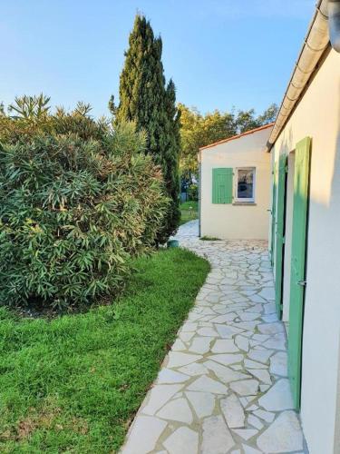 una pasarela de piedra junto a un edificio con una puerta verde en Chambre spacieuse et calme en Grand-Village-Plage