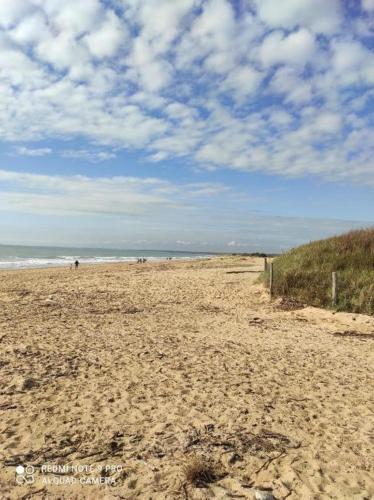 a sandy beach with people walking on the beach at Chambre spacieuse et calme in Grand-Village-Plage