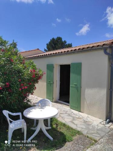 eine Terrasse mit einem Tisch und 2 Stühlen sowie ein Gebäude in der Unterkunft Chambre spacieuse et calme in Grand-Village-Plage