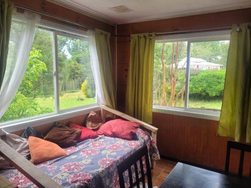 a bedroom with a bed with pillows and a window at CABAÑAS ISITEPUAL 5 min aeropuerto y 10 min del centro in Puerto Montt