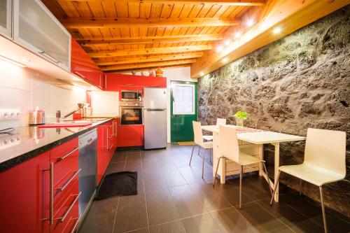 a kitchen with red cabinets and a table and chairs at Stone Home Casa do Caisinho Pico island in Terra Alta