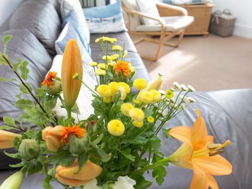 a bouquet of flowers sitting on a couch at Pass the Keys Modern 2 Bedroom Apartment with stunning Sea Views in Trearddur