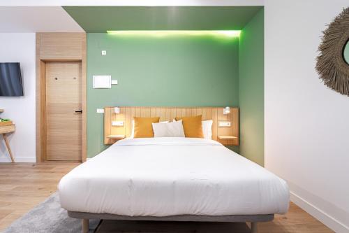 sypialnia z dużym białym łóżkiem i zielonymi ścianami w obiekcie Vallecas Suites by Olala Homes w Madrycie