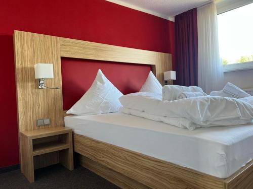 a bedroom with a large bed with a red wall at Hotel Ziegenkrug - Pritzwalk in Pritzwalk