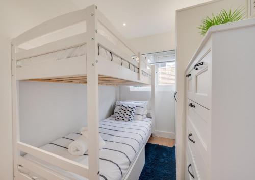 ein weißes Etagenbett in einem weißen Zimmer mit einer Treppe in der Unterkunft Sea Breeze in Newton