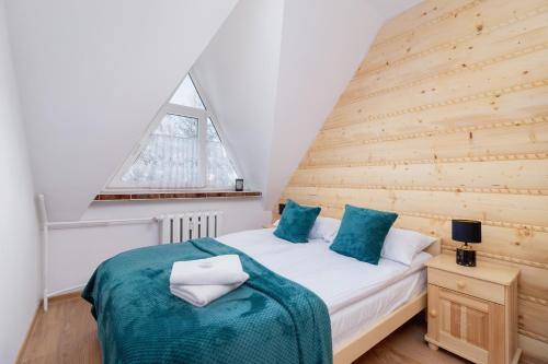 a bedroom with a bed with a wooden wall at Pardałówka Mountain View Apartments Zakopane by Renters in Zakopane