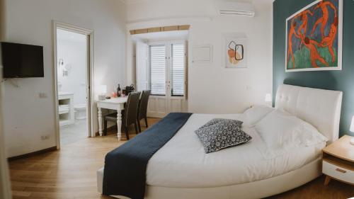 een slaapkamer met een bed, een bureau en een tafel bij Maravigghia Palermo Rooms in Palermo